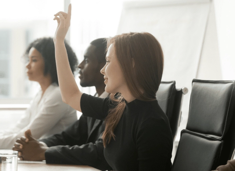 une femme lève la main pour répondre à une question