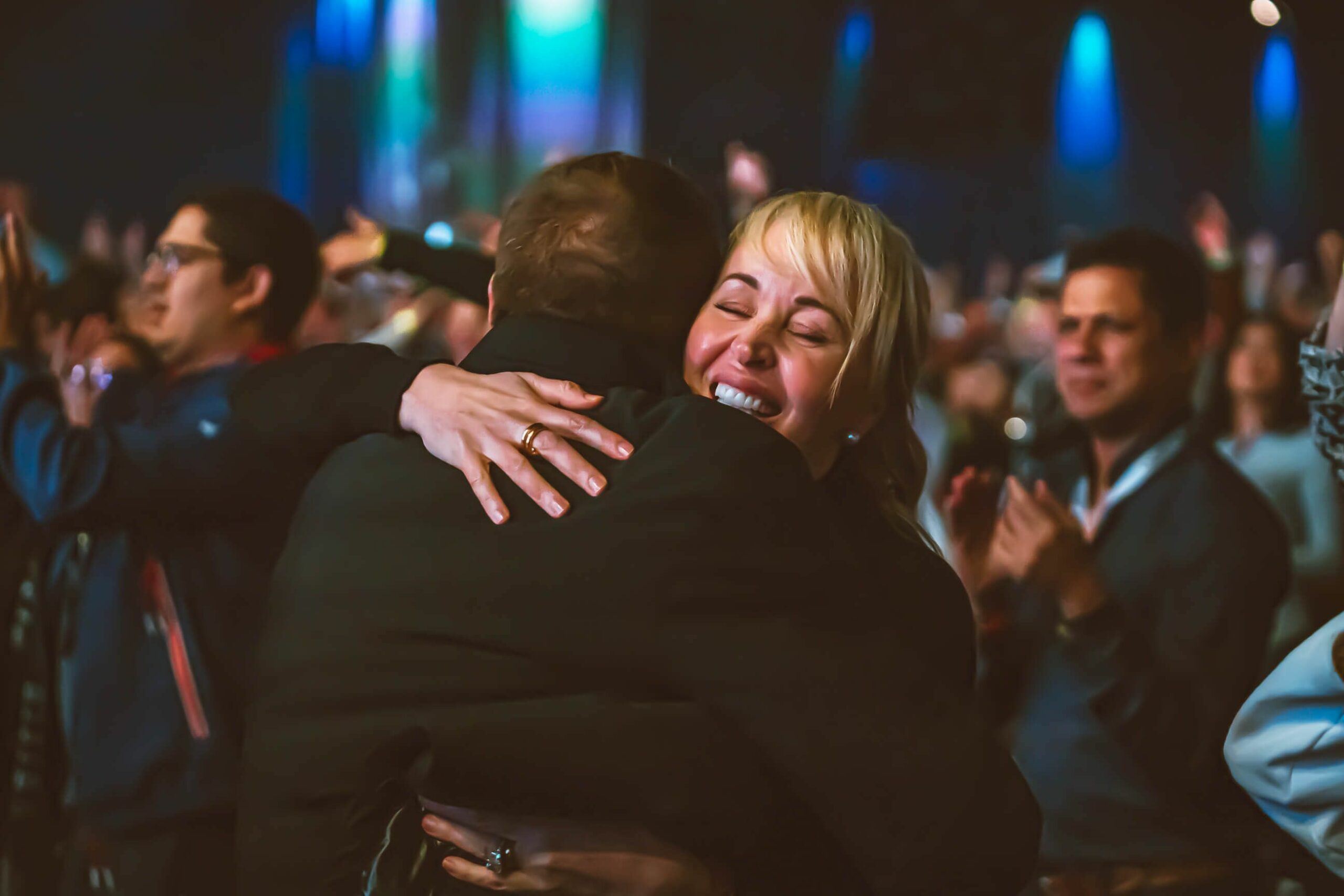 une femme serre un homme dans ses bras dans une foule lors d'un concert.